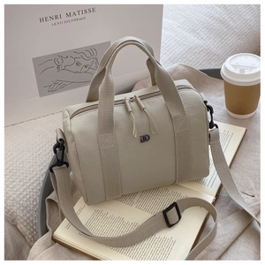 Détail du sac boston en nylon beige avec poignées en toile et bandoulière réglable