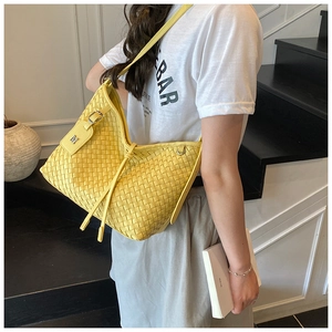 Side view of a yellow woven tote bag featuring a silver M tag and drawstring closure