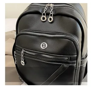 Dettaglio della pelle nera con cerniere argentate e logo metallico sullo zaino donna
