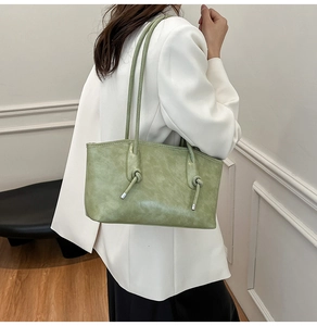 Détail du sac cabas vert clair avec bandoulière nouée et texture cuir sur blazer blanc