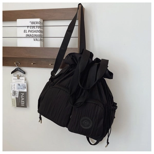 Detail of black drawstring nylon backpack with multiple zippered pockets and wide straps