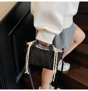 Detail of black nylon bucket bag featuring a grey drawstring closure and woven rope handle