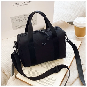 Gros plan d'un sac Boston noir avec logo DD argenté, sangle en nylon et décor artistique