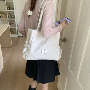 Detail of creamy white tote bag featuring embossed butterfly textures and satin bow