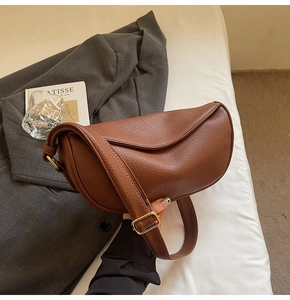 Detail of brown litchi pattern leather dumpling bag with golden metal buckle and strap