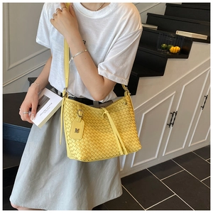 Detailed view of yellow woven leather tote bag with M charm and adjustable strap