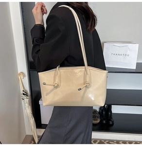 Détail du sac cabas en cuir crème avec bretelles à nœuds porté à l'épaule au quotidien