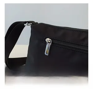 Detailed macro view of high-quality silver metal zipper on a black canvas crossbody bag