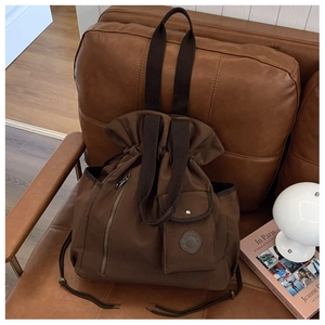 Detail of a dark brown canvas drawstring bucket bag with a retro utilitarian texture
