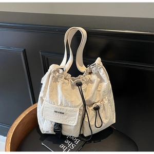 Detailansicht der cremefarbenen Nylontasche mit Kordelzug und vorderer Schnallentasche