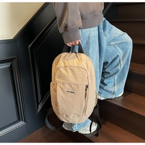 Detail of light brown nylon backpack with logo and adjustable straps on stairs