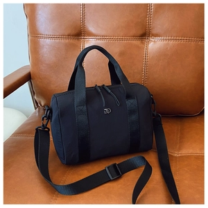 Détail du sac Boston noir en nylon avec doubles poignées et logo en métal argenté