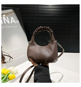 Detail of dark brown leather crescent bag with ruched handle and detachable strap