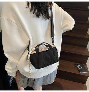Detail of black drawstring bucket bag with woven rope accent and adjustable nylon strap