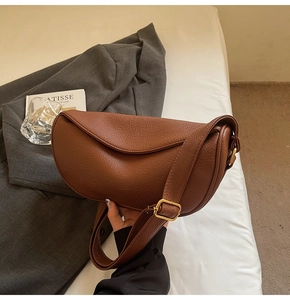 Detail of caramel crescent crossbody bag with lychee texture and gold metal buckle