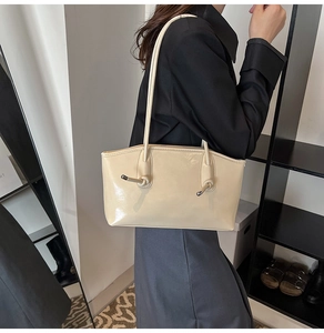 Détail du sac d'épaule crème brillant orné de décorations métalliques nouées uniques