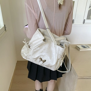 Detailed close-up of a large cream tote bag featuring a silver butterfly metal buckle