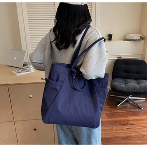 Detail of navy blue tote bag featuring side drawstring pocket and durable canvas texture