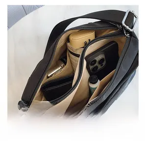Internal view of large capacity black nylon crossbody bag showing spacious storage compartments