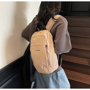 Nylon backpack close-up showing beige wrinkled texture and zip pocket detail with logo