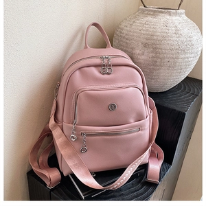 Detailed close-up of a pink textured leather backpack with silver zippers and metal ring pulls
