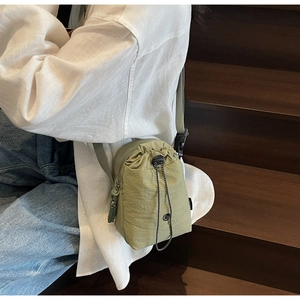 Petit sac bandoulière en nylon olive imperméable porté par un mannequin en extérieur