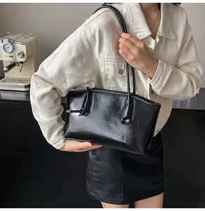 Grand sac à bandoulière noir chic avec finition cirée brillante porté par un mannequin