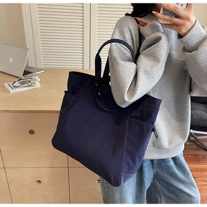 Detail of navy blue canvas tote bag side pocket with adjustable drawstring toggle