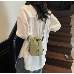 Détail d'un sac seau vert clair à cordon en nylon imperméable avec texture froissée