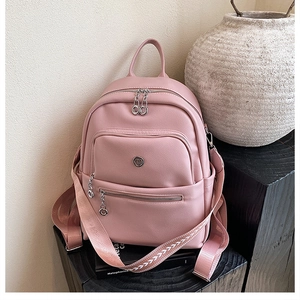 Detail of pink PU leather backpack with wide fabric straps on a wooden base