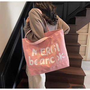 Detail of pink canvas tote bag with white Merci print for stylish casual daily use