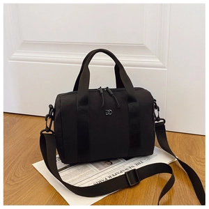 Détail du sac bandoulière en nylon noir avec logo en métal et poignées en sangle