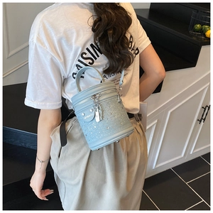 Détail du sac seau en denim bleu clair avec cristaux étincelants et garnitures argentées