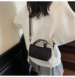 Close-up of black canvas bucket bag featuring decorative black and white braided rope details