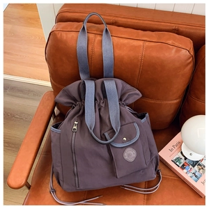 Detail of purple pleated bucket bag with drawstring closure and side zipper pocket