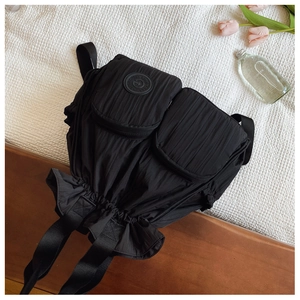 Top view of black drawstring backpack with double square front pockets on white fabric