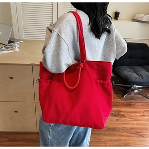 Detailed view of spacious red canvas tote bag featuring practical side storage pockets