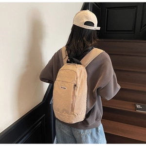 Detailed back view of a khaki nylon backpack on a model showing straps and texture