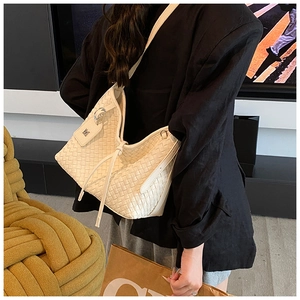 Detail view of cream leather woven hobo bag with adjustable strap on a female model