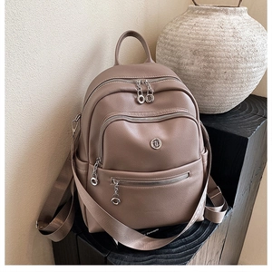 Detailed close-up of khaki lychee grain leather backpack with multiple zipper pockets