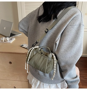 Detail of olive green nylon drawstring bucket bag showing pleated texture and cord accents