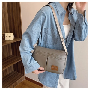 Detail of grey canvas crossbody bag with multiple zip compartments and adjustable strap