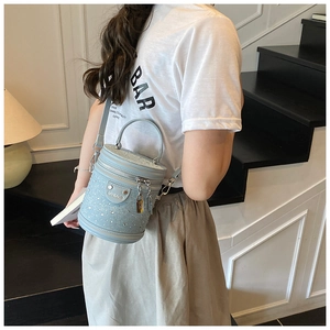 Sac seau bleu clair orné de strass avec bandoulière amovible porté par une mannequin