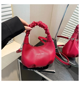 Détail du sac croissant rouge en cuir avec poignée froncée et bandoulière pour femme