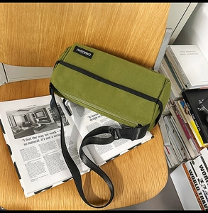 Détail du sac bandoulière en toile vert militaire avec fermeture éclair noire et logo