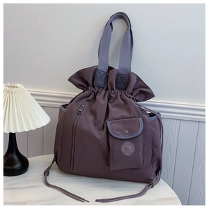 Detail of plum purple drawstring nylon tote bag with functional pockets on marble surface