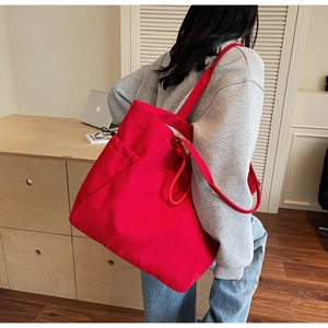 Detail of red large capacity canvas tote bag with wide shoulder strap on casual outfit