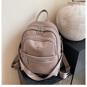 Detail of cocoa brown faux leather backpack with multiple zippers on wooden stand