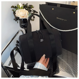 Vue détaillée d'un sac cylindrique noir avec poignées en tissu et logo métallique