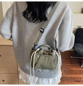 Detail of olive green drawstring bucket bag with textured fabric and woven handle